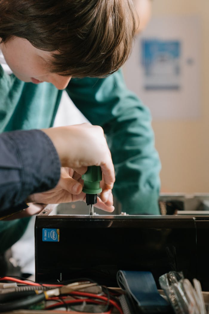 experience-img Close-up of hands repairing a computer with a screwdriver inside.